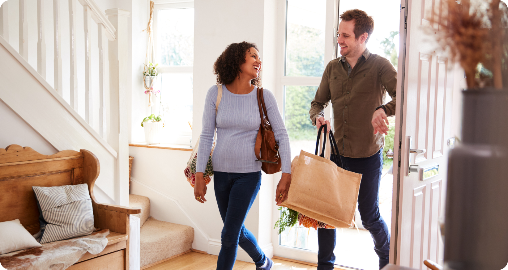 A man and a woman return home with shopping bags