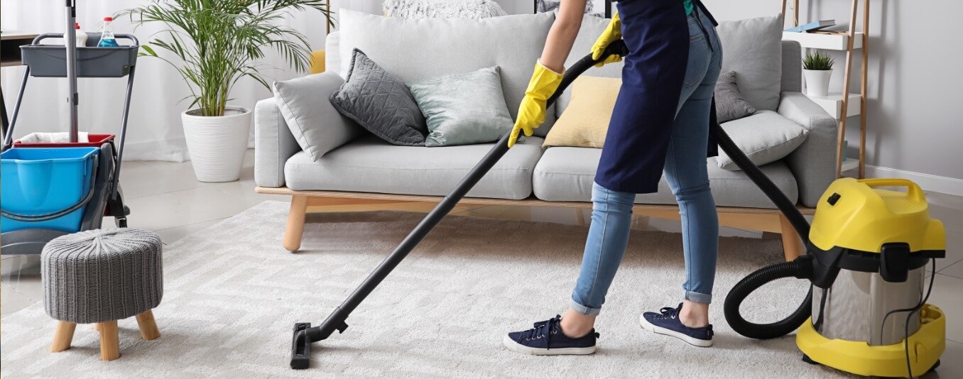 Donna delle pulizie che passa l'aspirapolvere sul tappeto della stanza