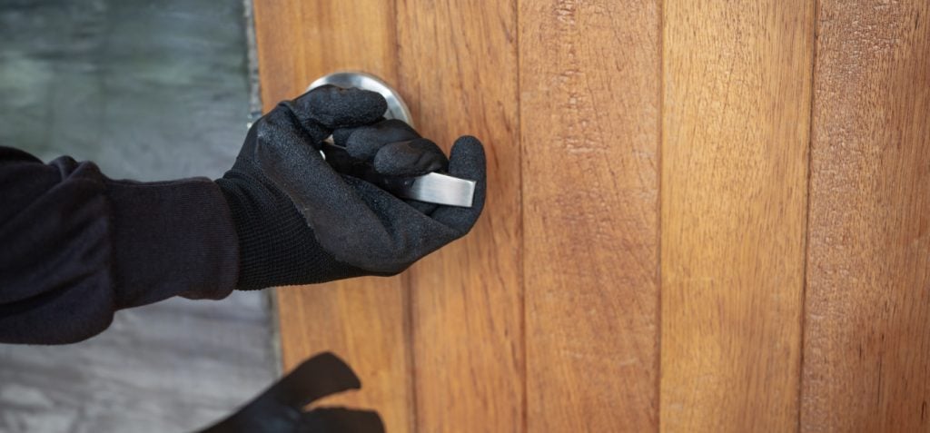 A gloved hand pressing a door handle