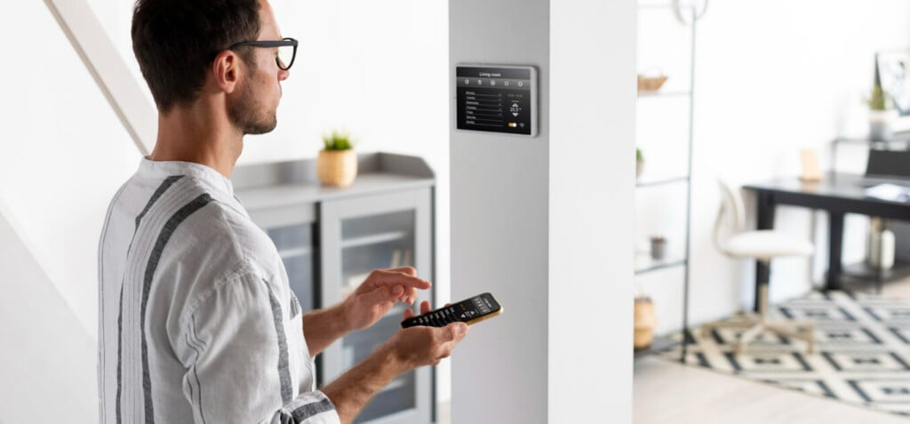 The man configures the thermostat using an app on the phone