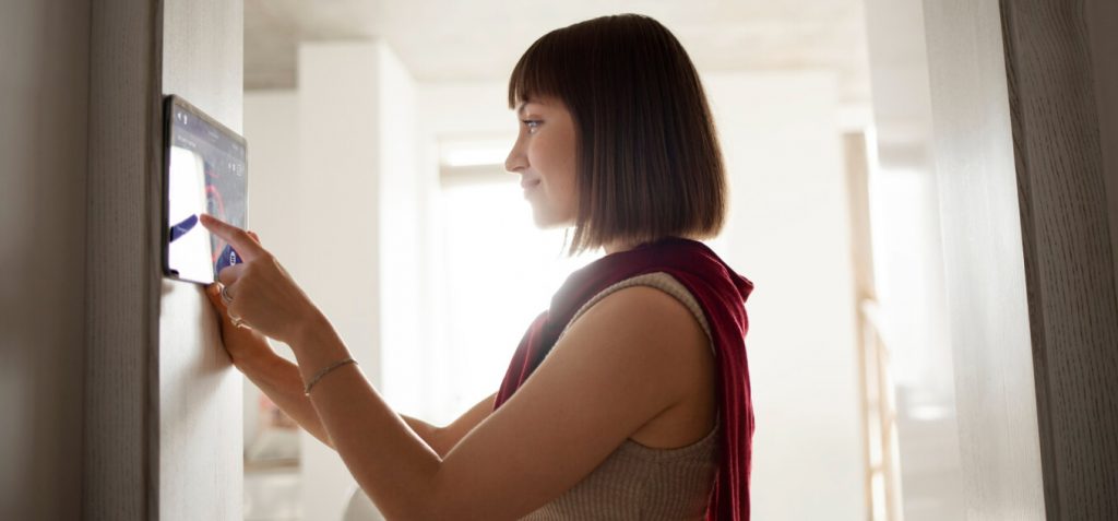 A woman setting up a smart thermostat