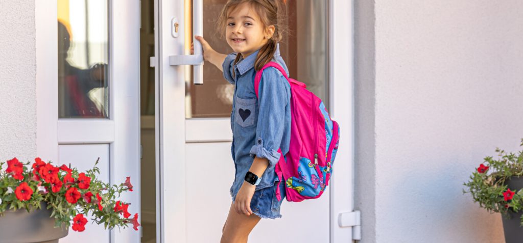 Uma garota com uma mochila abre a porta da frente