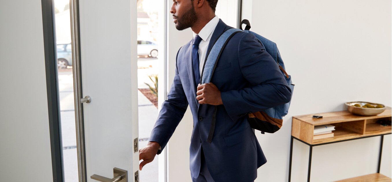 a man in a suit and with a backpack on his back leaves the room