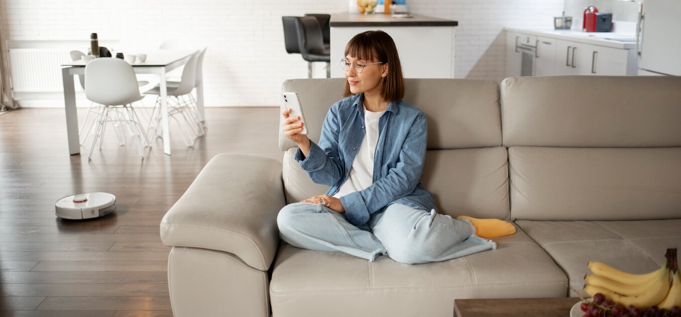 a woman sitting on the sofa in the living room is using a smartphone