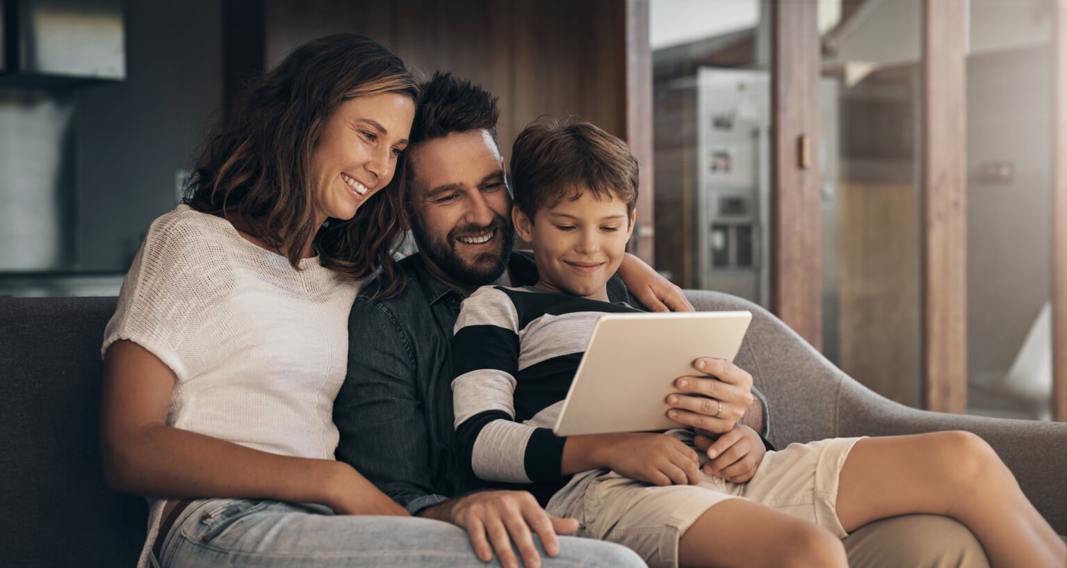 szczęśliwa trzyosobowa rodzina korzysta z inteligentnej automatyki domowej
