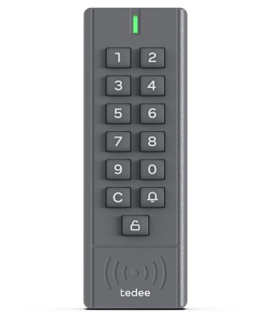 An image of a Tedee Keypad. This vertical, rectangular smart door lock accessory is dark grey and features a series of buttons arranged in two columns. At the top, an LED indicator is followed by numerical buttons from one to zero, a 'C' button for cancelling, a bell button for notifications, and an unlock button. Each button has white numbering and symbols. Below the buttons, symbols indicate wireless connectivity and display the Tedee logo.